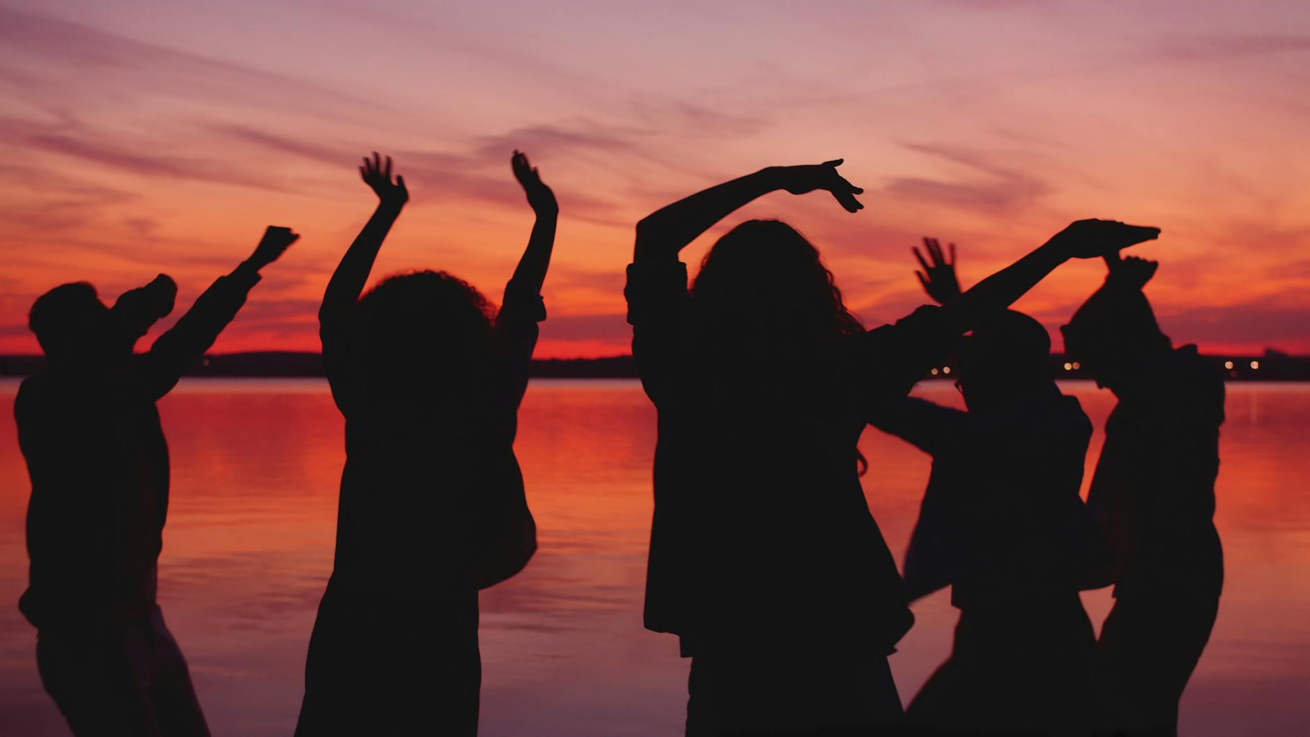silhouettes of friends dancing at sunset
