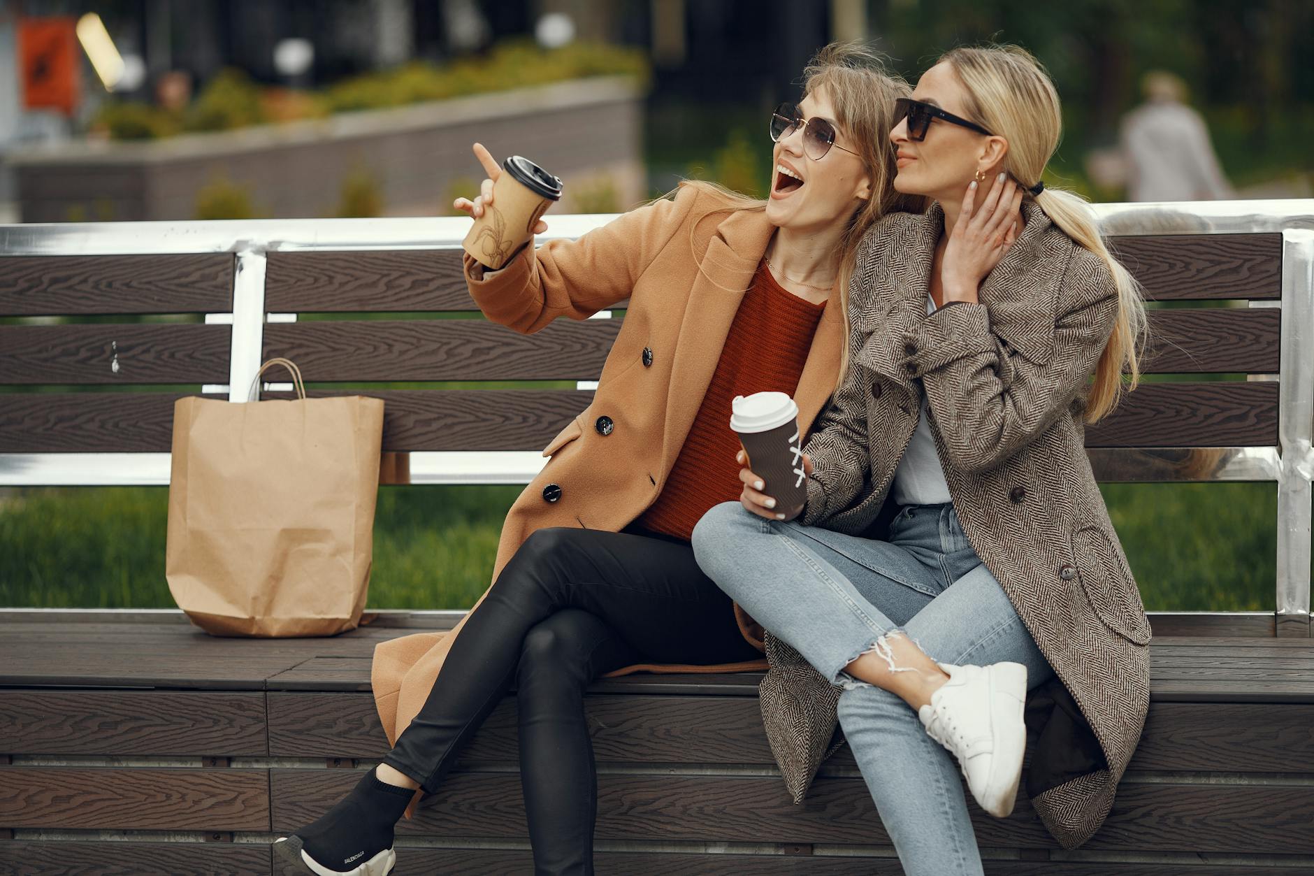 women having coffee on bench
