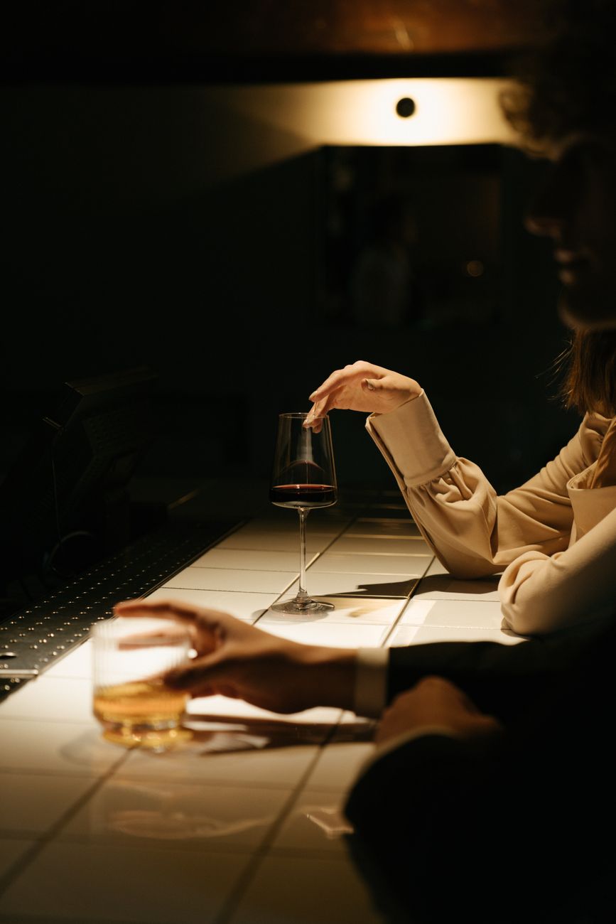 woman in white long sleeve shirt holding clear drinking glass