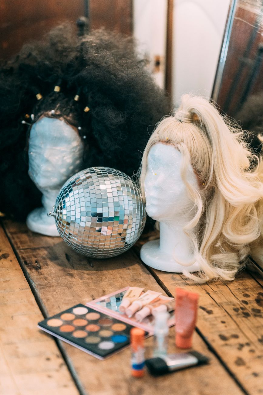 wigs on mannequins near sparkling disco ball and palette